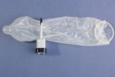 Condom in a lock on a blue background.の写真素材