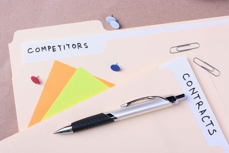 Manila competitors and contracts folders laying next to business supplies.の写真素材