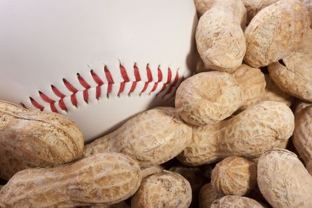 Nuts Peanuts on a table together with a baseball ball.