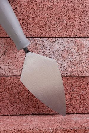 Stonemason's trowel on a background of red bricks.の写真素材