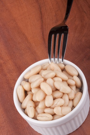 White canned beans in a white ceramic bowl with a fork.の写真素材