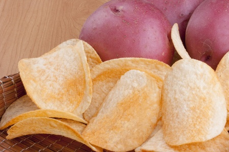 Potato chips with a potato on a wooden tray.の写真素材