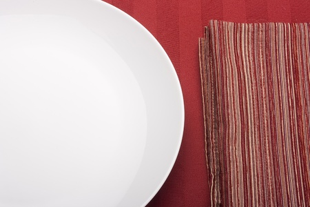 White plate on a red background with a red cloth.の写真素材