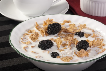 Light morning meal from cereals with berries of a blackberry and milk, in a coffee cup.