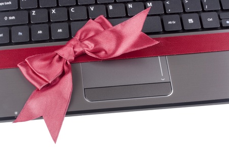 Personal computer as a gift tied with a red ribbon with a bow.の写真素材