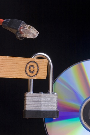Copyright symbol on a piece of wood next to a CD and an internet cable.の写真素材