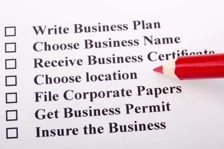 A red pencil laying on a paper with a checklist for starting a business.の写真素材