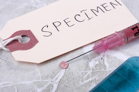 Syringe with pink liquid next to a tag which says 