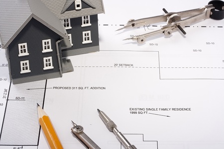 House model and drafting tools on a construction plan.