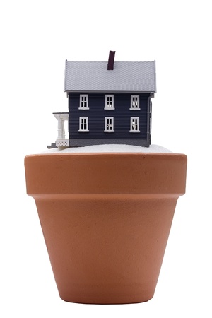 Model of the house on the sand falling asleep in a ceramic flower pot.の写真素材