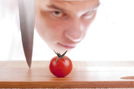 The young chef is considering to cut a tomato.の写真素材