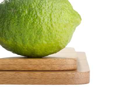 Green lime on a cutting board on a white background.