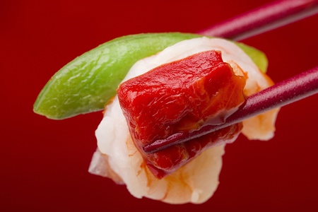 Food from an Asian appetizer in red chopsticks on a red background.の写真素材