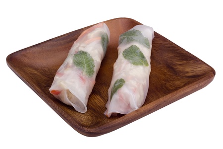Asian spring rolls in rice paper on a wooden plate.