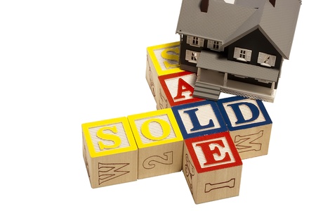 House model next to blocks spelling out the word sale and sold.の写真素材
