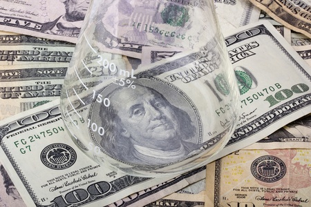 An erlenmeyer flask standing on various denominations of American money.の写真素材