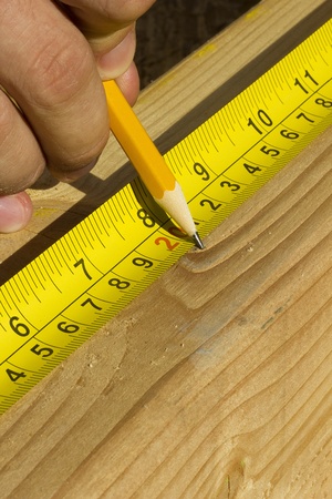 Closeup view of a worker measuring a piece of wood.の写真素材
