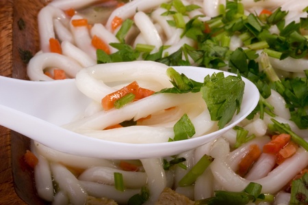 Asian noodle soup in a wooden bowl and a white spoon.の写真素材