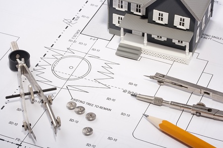 House model and drafting tools on a construction plan.