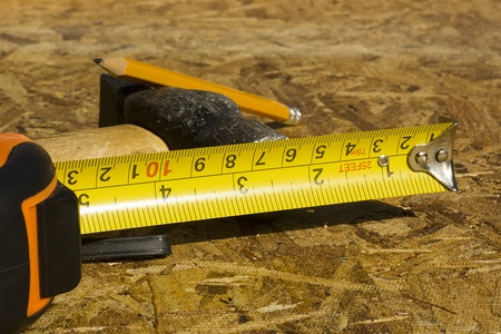 Measuring tape and other construction tools in the background on plywood.の写真素材