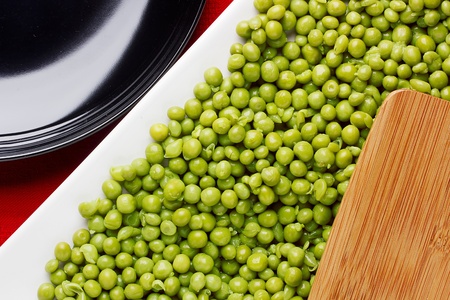 Directly above photograph of an edge of a cutting board and green peas.の写真素材