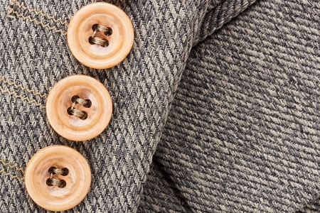 Close-up photograph of three orange buttons on gray fabric. の写真素材