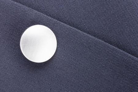 Close-up photograph of a silver button on gray material.