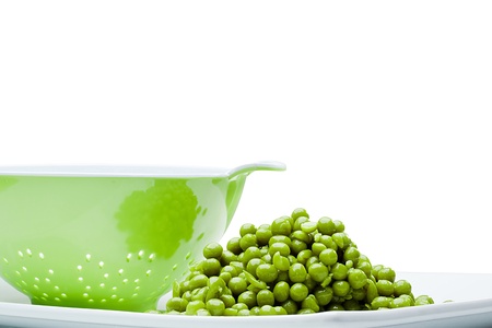 Close-up photograph of a pile of green peas next to a colander.の写真素材