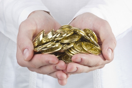 Close-up photograph of man's hands holding golden coins.の写真素材