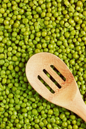 Full frame photograph of a wooden spoon on green peas.の写真素材