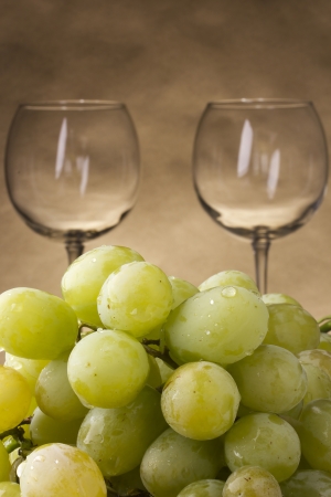 Two empty glasses with a bunch of grapes.の写真素材