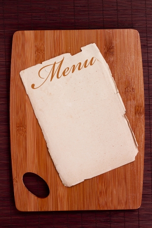 Ancient sheet menu on a wooden chopping board.の写真素材
