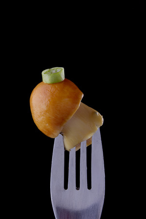 White Mushroom on a fork with a piece of green onion.の写真素材
