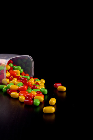 Colorful dragees on black wooden table surface.の写真素材