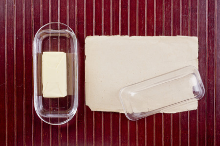 Butterdish of glass on a wooden surface with old paper.