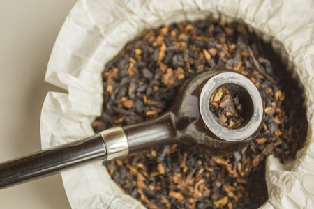 Smoking pipe on a handful of smoking tobacco.の写真素材