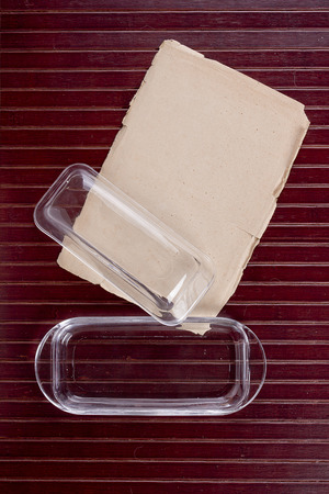 Butterdish of glass on a wooden surface with old paper.の写真素材