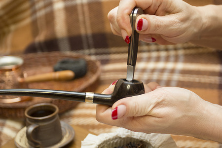 Female hand tamping tobacco smoking pipe.の写真素材