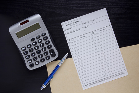 Filling the financial invoice form and calculator with pen.