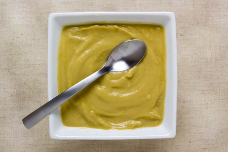 Pea cream soup in a square ceramic plate.