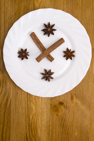 Styling plates under the abstract clock, cinnamon sticks as a shooter, anise - numbers.の写真素材