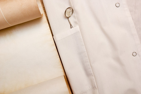 Dental mirror for inspection of the oral cavity in the breast near the white coat parchment.の写真素材