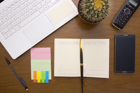 Office desk with office items - diary and laptop, cactus and phones.の写真素材