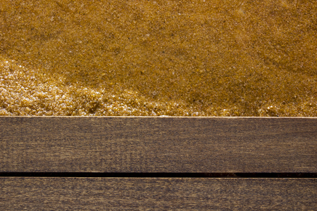 The edge of the water with wooden flooring and wet sand.の写真素材