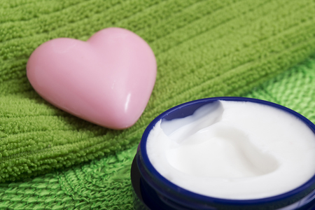 Soap in the shape of a heart, and a cream in a container for cosmetics.の写真素材