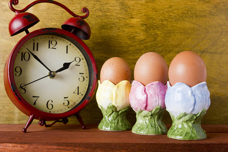 Eggs in the decorative ceramic stands and alarm clockの写真素材