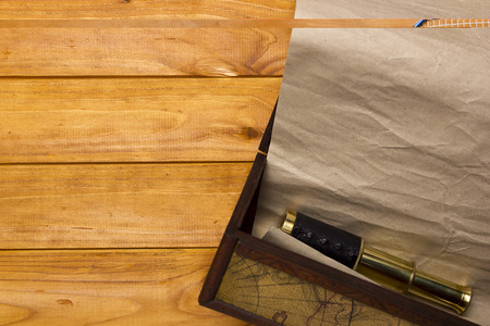 Scroll and telescope in the old box on a wooden table