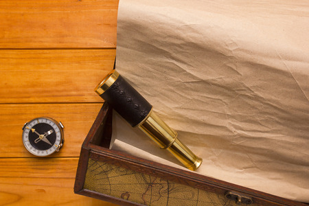 Scroll in the box, telescope and compass on a wooden backgroundの写真素材