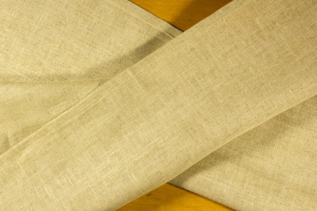 Mustard linen cloth on a wooden background