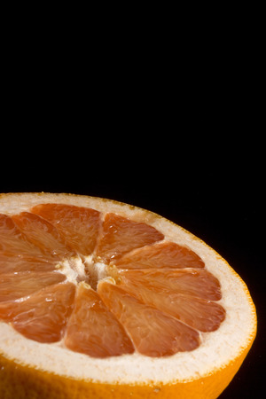 Cut half of juicy ripe grapefruit on the black backgroundの写真素材